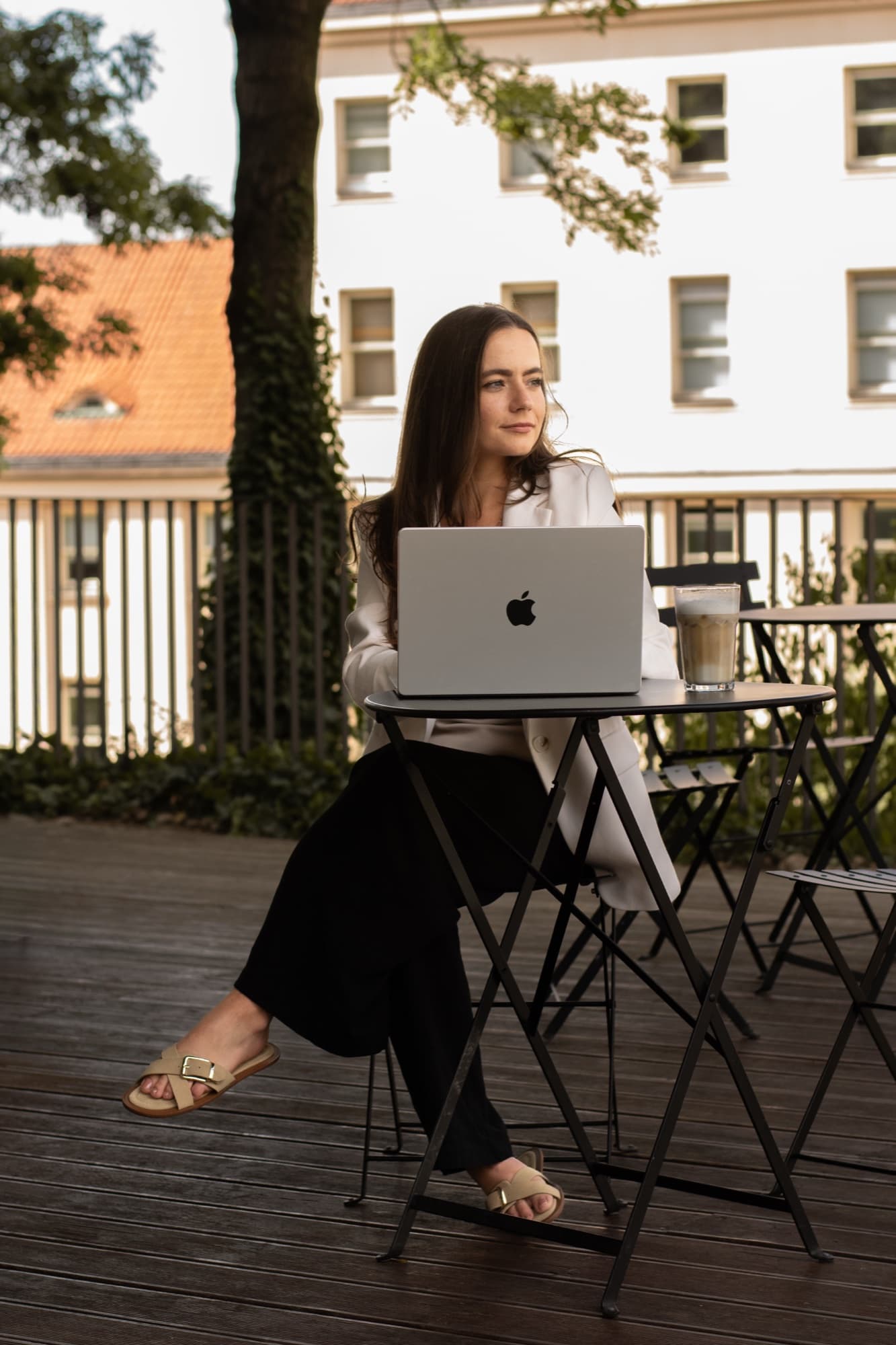 Petra Venušová sedí s notebookem u stolku na kavárenské terase